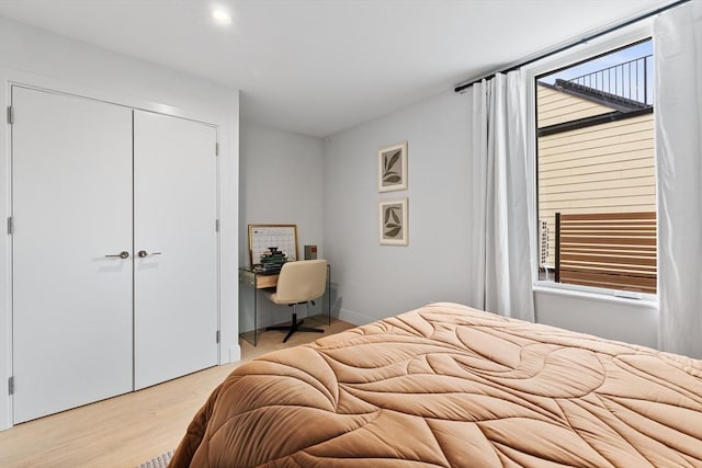 bedroom featuring light hardwood / wood-style floors, multiple windows, and a closet