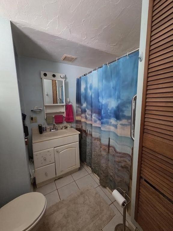 full bathroom featuring visible vents, tile patterned flooring, vanity, curtained shower, and toilet
