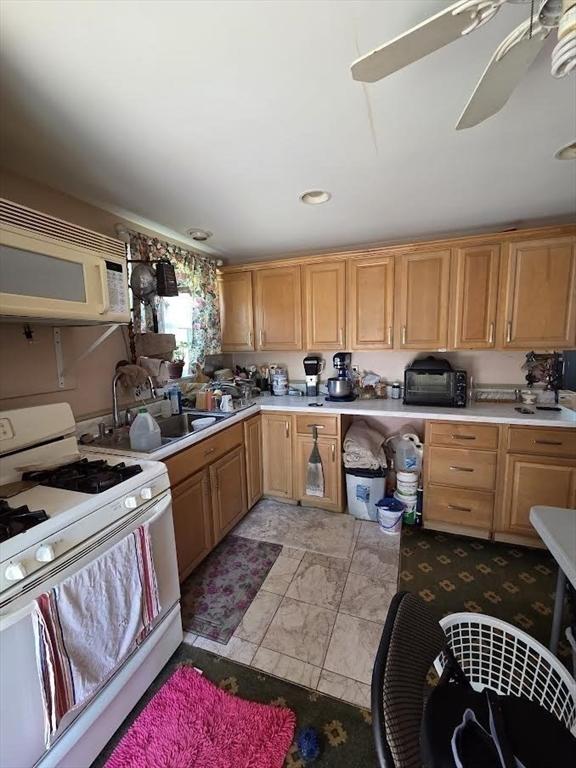 kitchen with white appliances, a ceiling fan, a sink, and light countertops