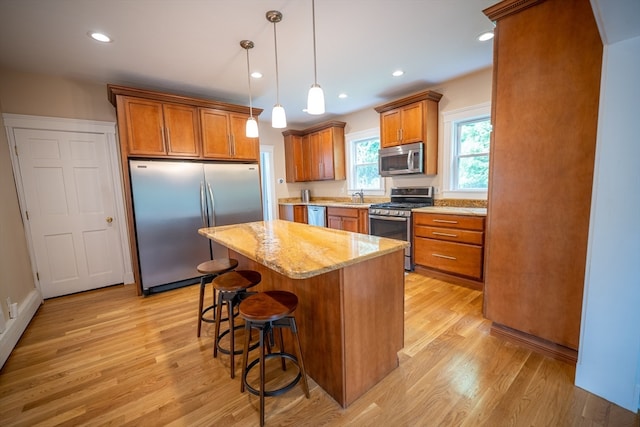 kitchen featuring pendant lighting, light wood-type flooring, a center island, and appliances with stainless steel finishes