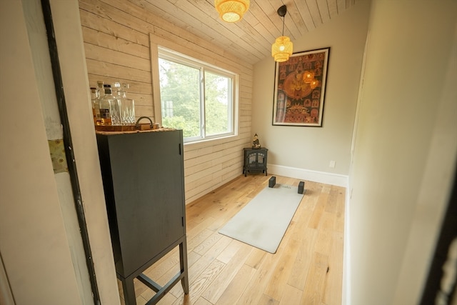 interior space with light wood-type flooring, a wood stove, and wooden walls