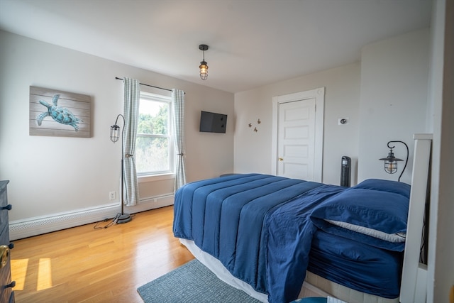 bedroom featuring a baseboard heating unit and light hardwood / wood-style floors