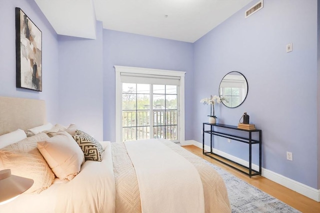 bedroom with wood finished floors, access to exterior, and baseboards