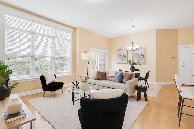 living area with a chandelier, light wood-style floors, and baseboards