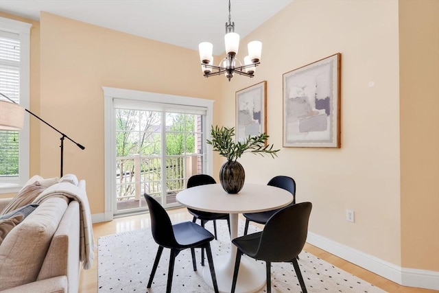 dining area with a chandelier, light wood-style floors, and baseboards