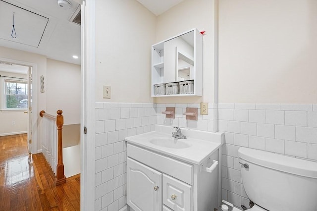 bathroom with tile walls, toilet, wood-type flooring, and vanity