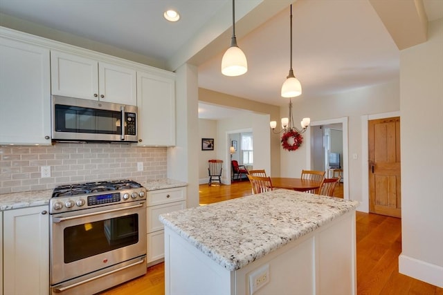 kitchen featuring backsplash, light stone countertops, light wood-style flooring, appliances with stainless steel finishes, and white cabinets