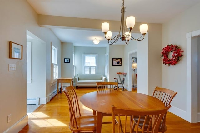 dining area featuring a baseboard heating unit, baseboards, light wood-type flooring, and a chandelier