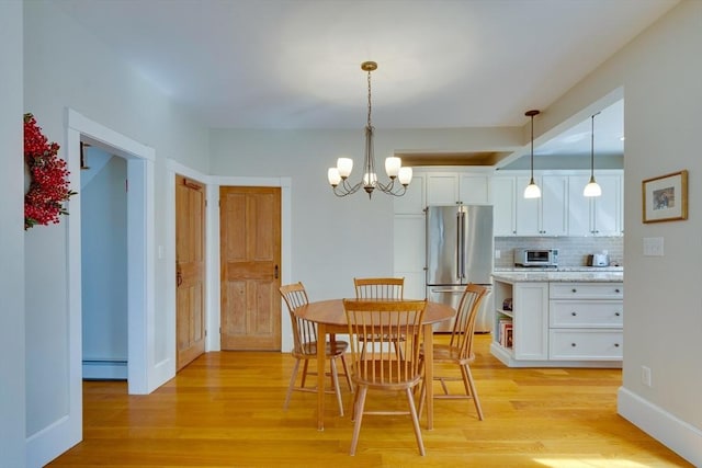 dining room featuring light wood-type flooring, a baseboard heating unit, baseboards, and a chandelier