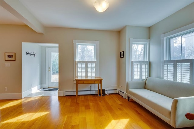 unfurnished room with beamed ceiling, a healthy amount of sunlight, light wood-type flooring, and baseboards