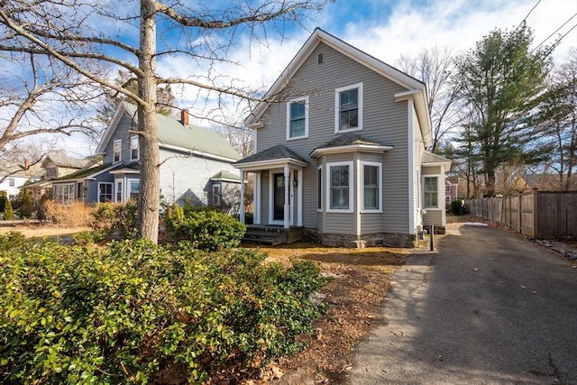 traditional home with aphalt driveway and fence