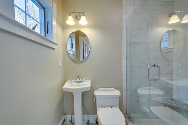 bathroom featuring a stall shower, toilet, baseboards, and a sink