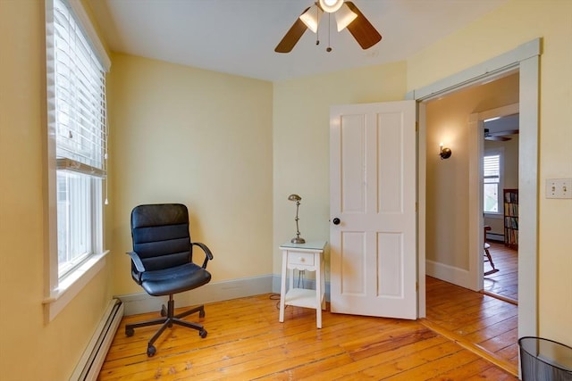 sitting room featuring a baseboard heating unit, baseboards, and hardwood / wood-style flooring