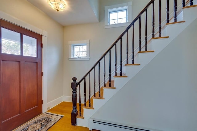 entrance foyer with a wealth of natural light, a baseboard radiator, baseboards, and wood finished floors