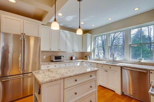 kitchen featuring backsplash, light wood-type flooring, a wealth of natural light, appliances with stainless steel finishes, and a sink