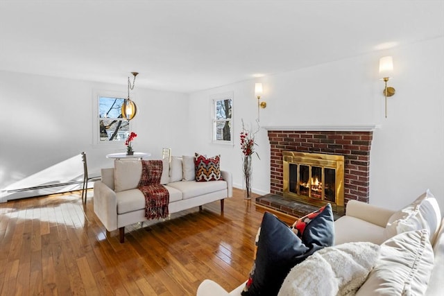 living room featuring a brick fireplace, wood-type flooring, and a baseboard heating unit