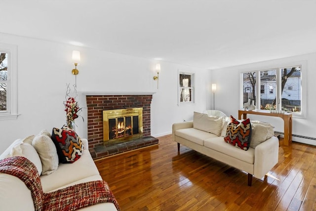 living room with wood-type flooring, a fireplace, and a baseboard heating unit