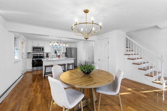 dining area with a notable chandelier, dark hardwood / wood-style floors, and a baseboard heating unit