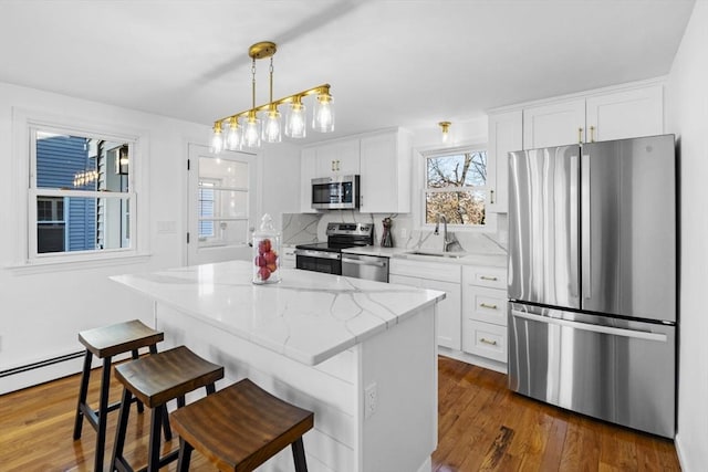 kitchen featuring a center island, white cabinets, sink, hanging light fixtures, and stainless steel appliances