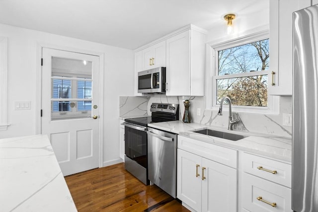 kitchen with light stone countertops, decorative backsplash, stainless steel appliances, sink, and white cabinetry