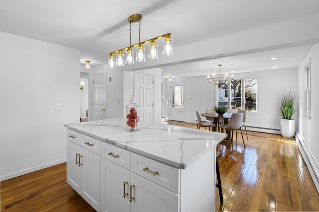 kitchen with white cabinets, decorative light fixtures, a kitchen island, and a baseboard radiator