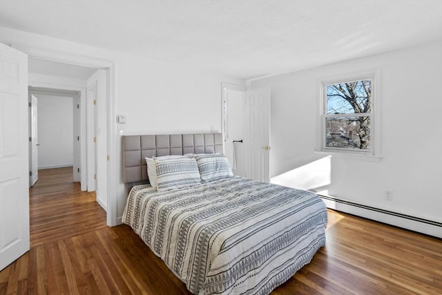 bedroom with dark hardwood / wood-style floors and baseboard heating