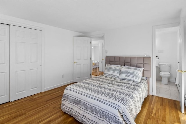 bedroom with hardwood / wood-style floors, ensuite bath, and a closet