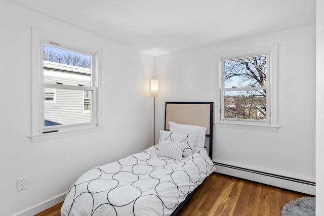 bedroom with dark hardwood / wood-style flooring, a baseboard radiator, and multiple windows