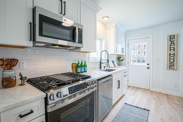 401 N End Blvd, Salisbury, MA 01952 - kitchen featuring stainless steel appliances, light wood-type flooring, white cabinets, backsplash, and light stone countertops