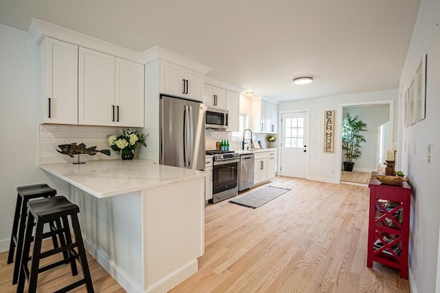 401 N End Blvd, Salisbury, MA 01952 - kitchen featuring appliances with stainless steel finishes, tasteful backsplash, a kitchen bar, and light wood-style floors