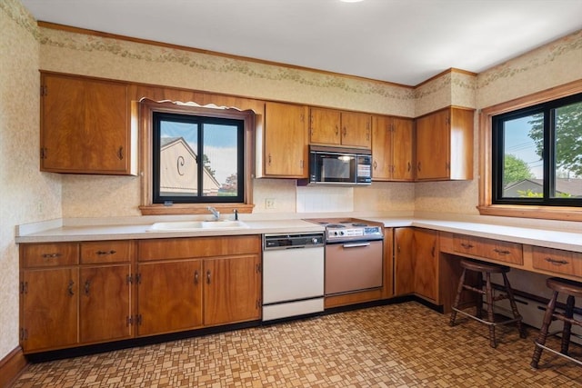 kitchen featuring dishwasher, a sink, black microwave, electric range oven, and brown cabinetry
