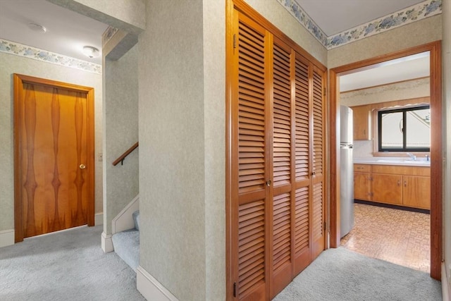 hall with light colored carpet, wallpapered walls, and stairway