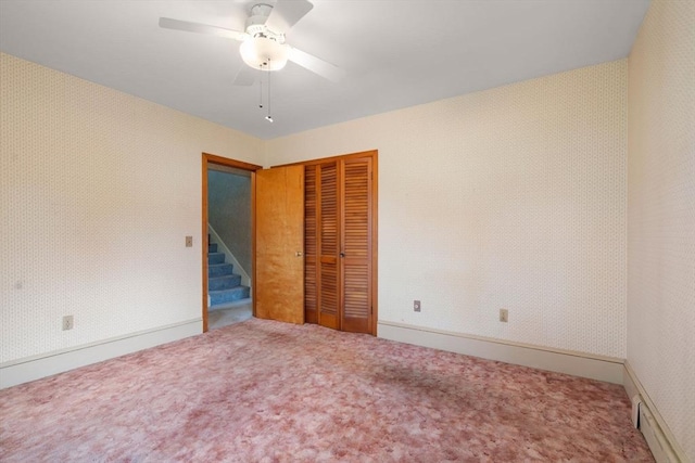 unfurnished bedroom featuring a closet, carpet, ceiling fan, a baseboard heating unit, and baseboards