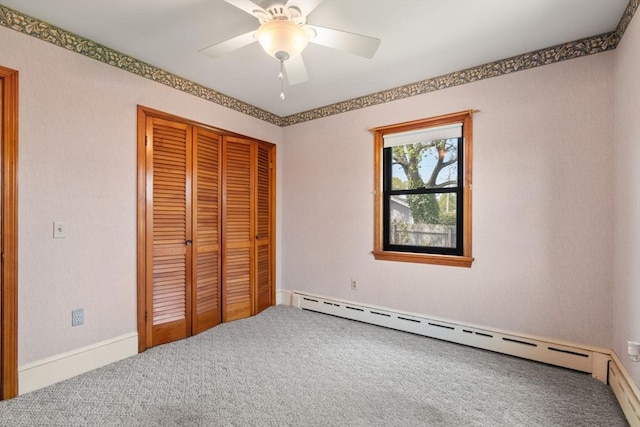 unfurnished bedroom with carpet flooring, baseboard heating, a closet, a ceiling fan, and baseboards