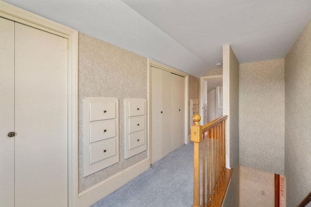 corridor featuring an upstairs landing, light colored carpet, and vaulted ceiling