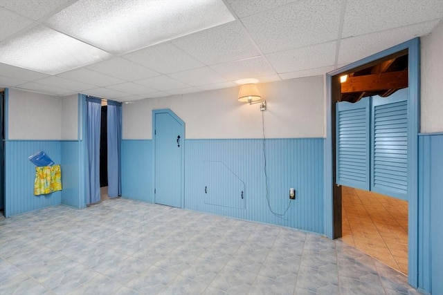 spare room with a drop ceiling and wainscoting