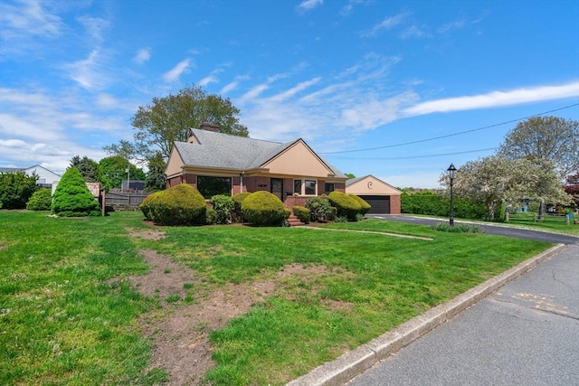 view of front of property featuring a front yard, brick siding, a detached garage, and a chimney