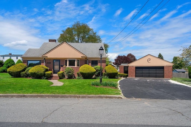 view of front facade featuring brick siding, asphalt driveway, and a front yard
