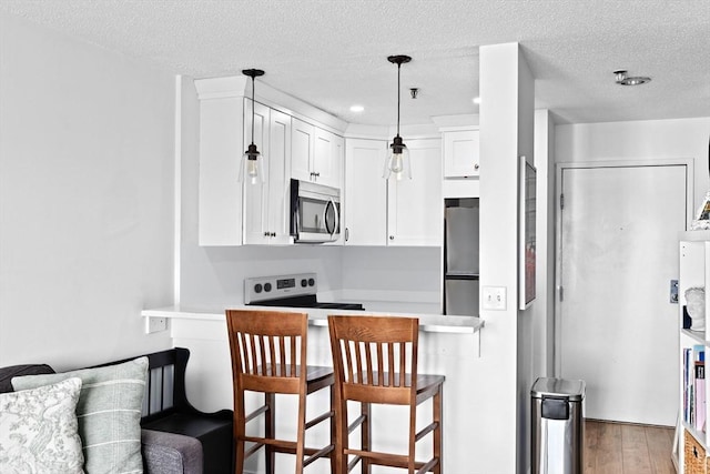 133 Commander Shea Blvd Unit 713, Quincy, MA 02171 - kitchen featuring appliances with stainless steel finishes, white cabinetry, a breakfast bar area, a textured ceiling, and wood finished floors