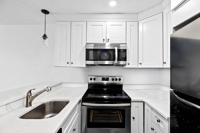 133 Commander Shea Blvd Unit 713, Quincy, MA 02171 - kitchen featuring appliances with stainless steel finishes, a sink, white cabinets, decorative light fixtures, and light stone countertops
