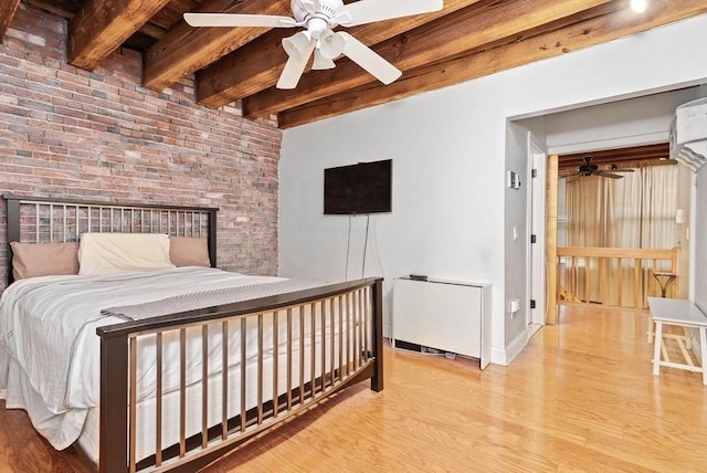 bedroom with baseboards, wood finished floors, brick wall, and beamed ceiling