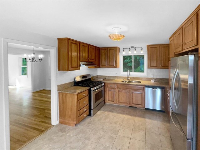 kitchen with decorative light fixtures, sink, stainless steel appliances, and a wealth of natural light