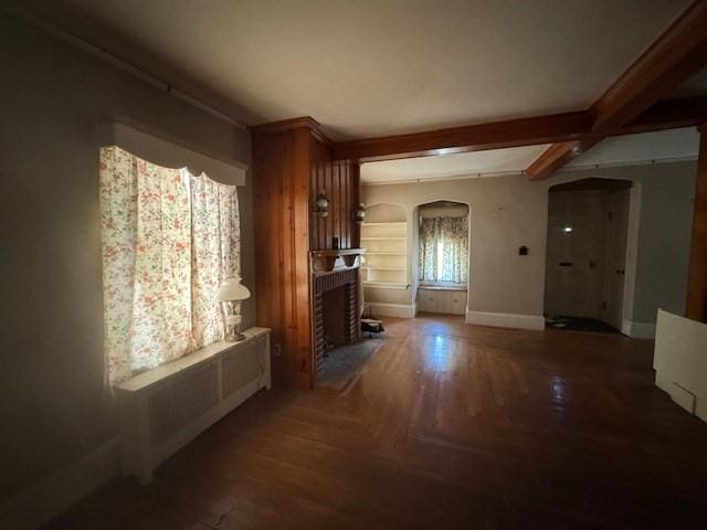 1002 Charles St, North Providence, RI 02904 - unfurnished living room with arched walkways, wood finished floors, beamed ceiling, and a brick fireplace