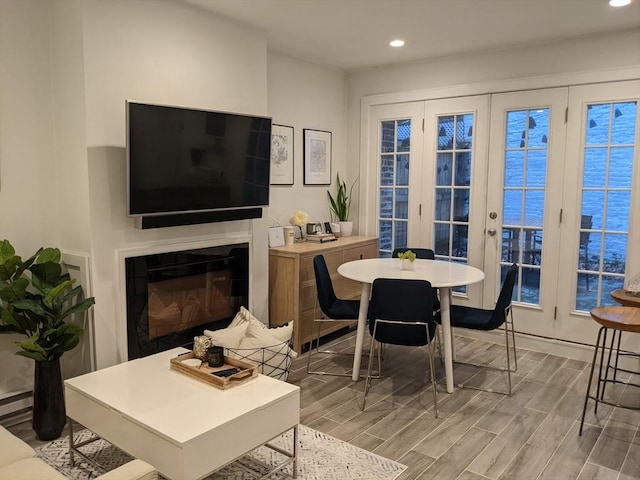 dining space with recessed lighting, wood finished floors, and a glass covered fireplace