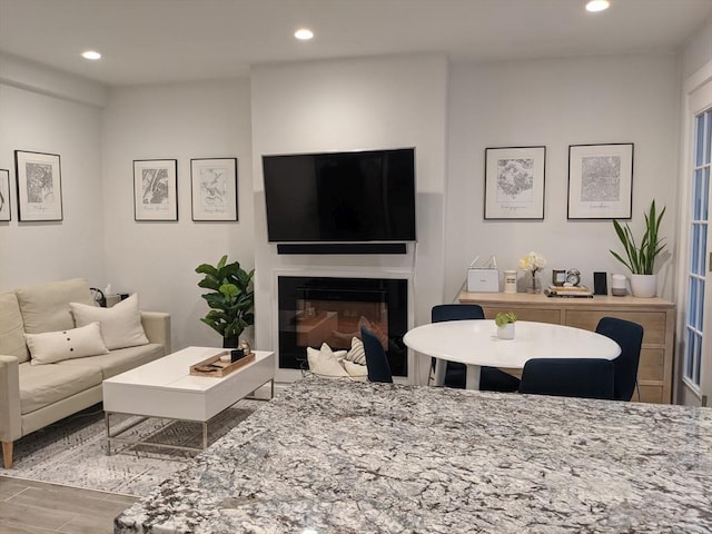 living room with wood finished floors, recessed lighting, and a glass covered fireplace