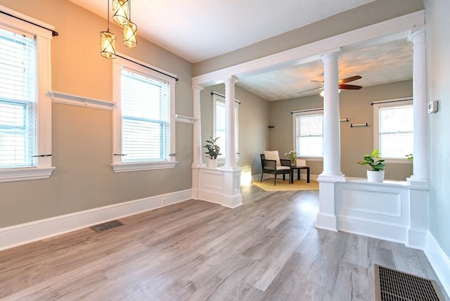 interior space featuring ceiling fan, wood finished floors, visible vents, and ornate columns