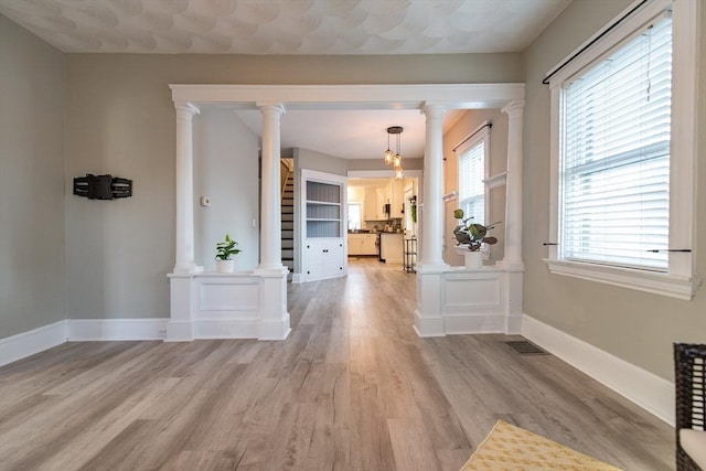 interior space featuring decorative columns and light wood finished floors