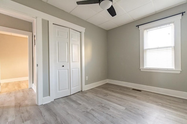 unfurnished bedroom with a paneled ceiling, a closet, visible vents, wood finished floors, and baseboards