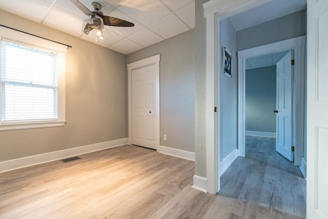 unfurnished room with visible vents, light wood-style flooring, baseboards, and a drop ceiling