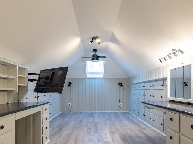 bonus room with light wood-type flooring, vaulted ceiling, and wooden walls